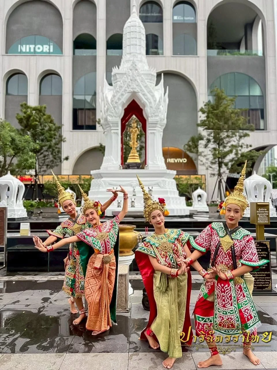 ผู้แสดงสี่คนในชุดยืนเครื่องหน้าศาลสีขาว